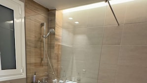 Een moderne badkamer met een douchecabine van glas, een wit toilet en een houten wastafelmeubel.