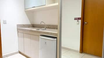 A compact kitchen with a built-in dishwasher, a countertop sink, and a wooden door.