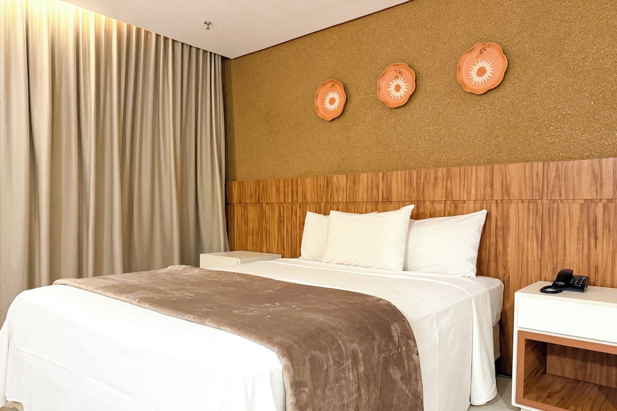 A hotel room with a bed, a nightstand, and a wall with three decorative plates.