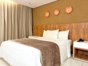 A hotel room with a bed, a nightstand, and a wall with three decorative plates. - STAY Vivence Suites  (Palmas)