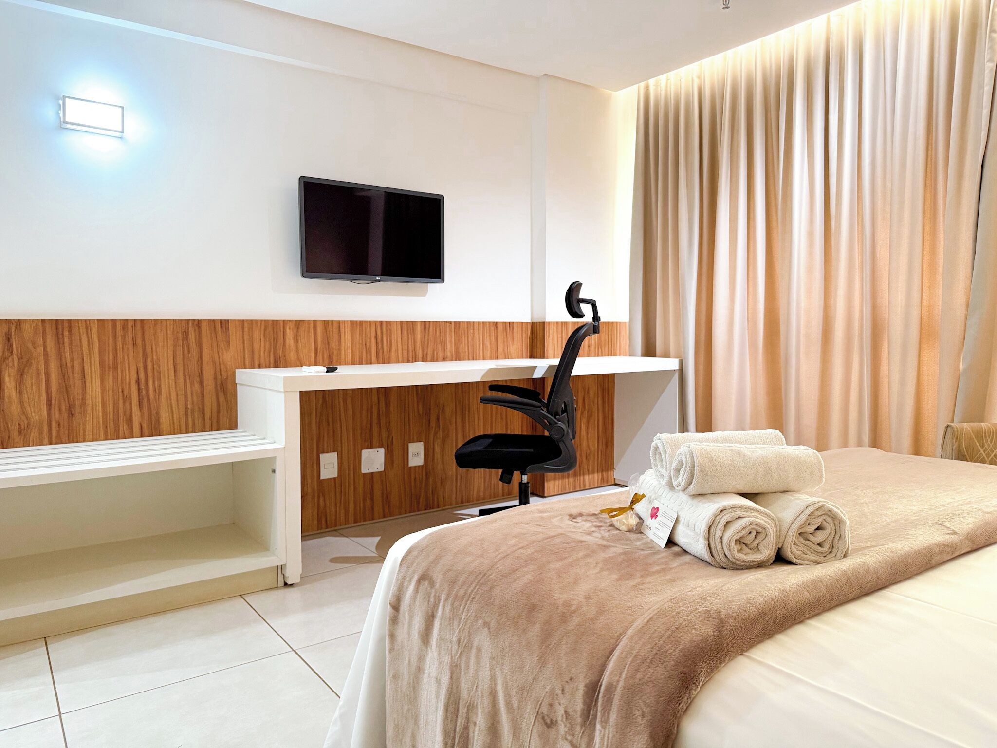 Hotellihuone, jossa on sänky, työpöytä tuolilla, televisio ja kylpyhuone.