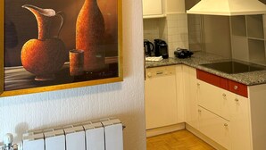 A kitchen with white cabinets, a painting of vases, and a modern stove. - Acropolis Elegant Apartment II (Athina)