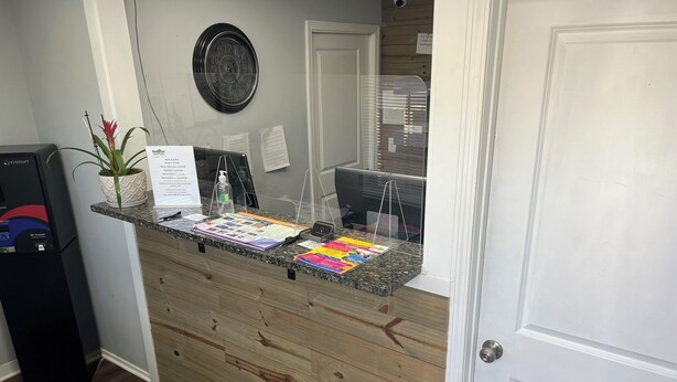 A reception desk with a wooden panel design, a clock, and various informational materials.
