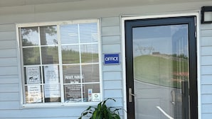 A building with a 'PRIVATE PARKING' sign, a 'DOG WASTE' sign, and an 'OFFICE' sign.