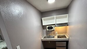 A compact kitchen with a microwave, sink, and a small table.