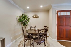 Un comedor con una mesa redonda, cuatro sillas, una planta en maceta y un adorno en la pared.