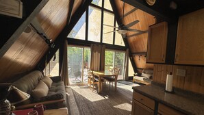 Un espace de vie chaleureux de style loft, comprenant un coin repas, une cuisine et une grande porte-fenêtre coulissante donnant sur l’extérieur.