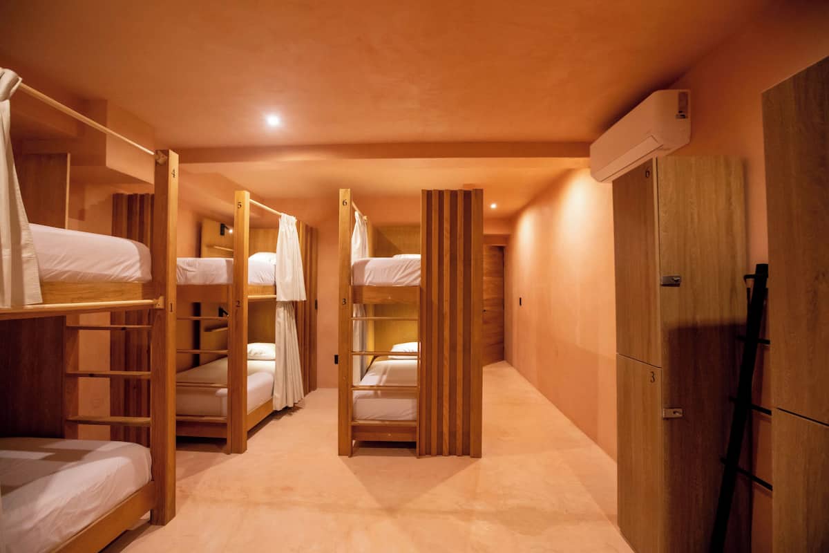 A hotel room with bunk beds, wooden furniture, and a wardrobe.