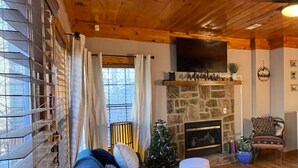 Un salón acogedor con un sofá azul, una chimenea de piedra y un árbol de Navidad.
