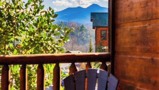 A wooden cabin with a view of a mountain range.