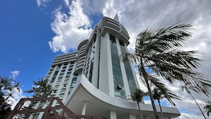 A modern hotel with a curved facade, large windows, and a prominent entrance with a staircase.
