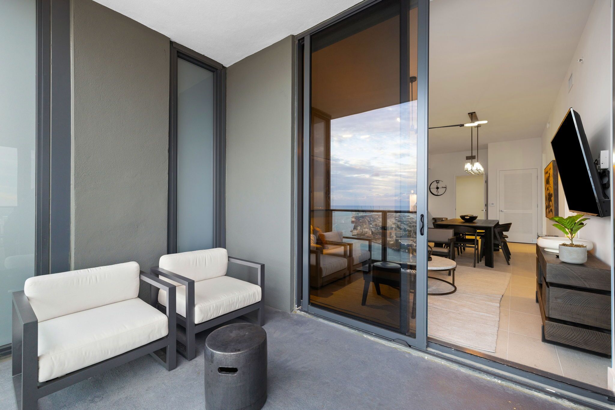 Un espace de vie moderne avec un balcon, des sièges, une table à manger et un téléviseur.
