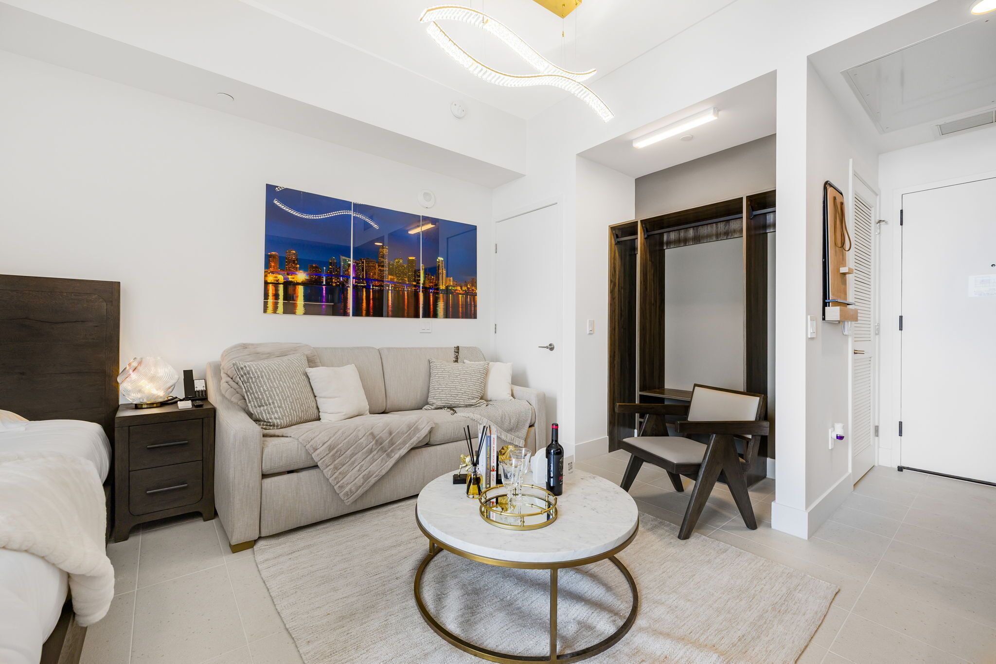 A modern hotel room with a bed, a sofa, a round coffee table, and a large mirror.