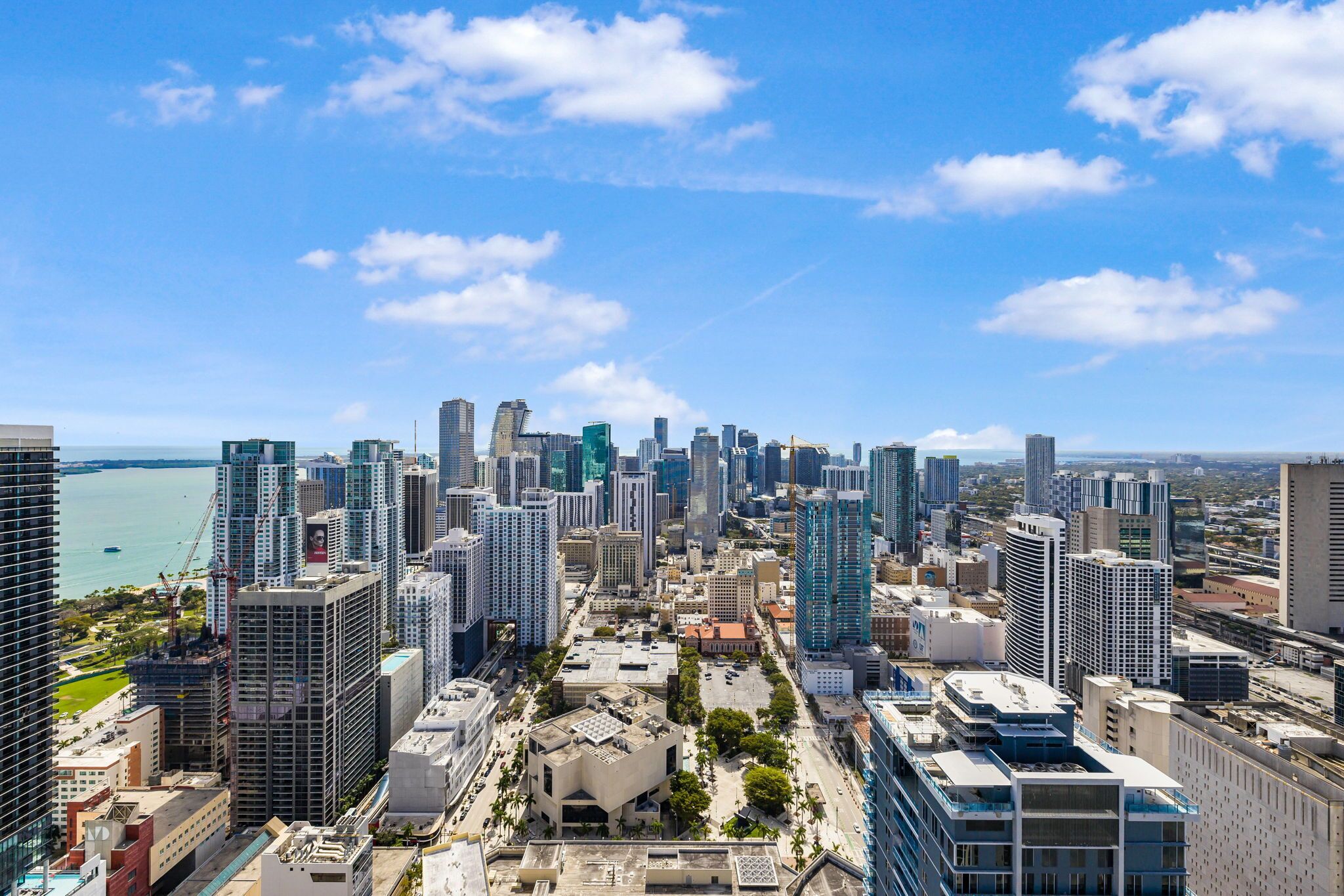 A cityscape with high-rise buildings, a waterfront, and a clear sky.