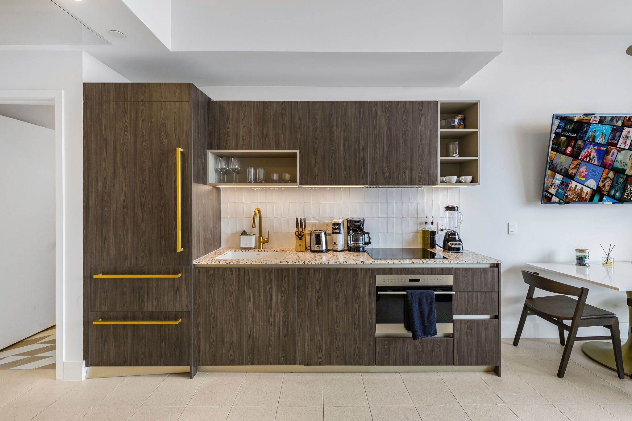 A modern kitchen with wooden cabinets, a countertop, and a dining area with a table and chair.
