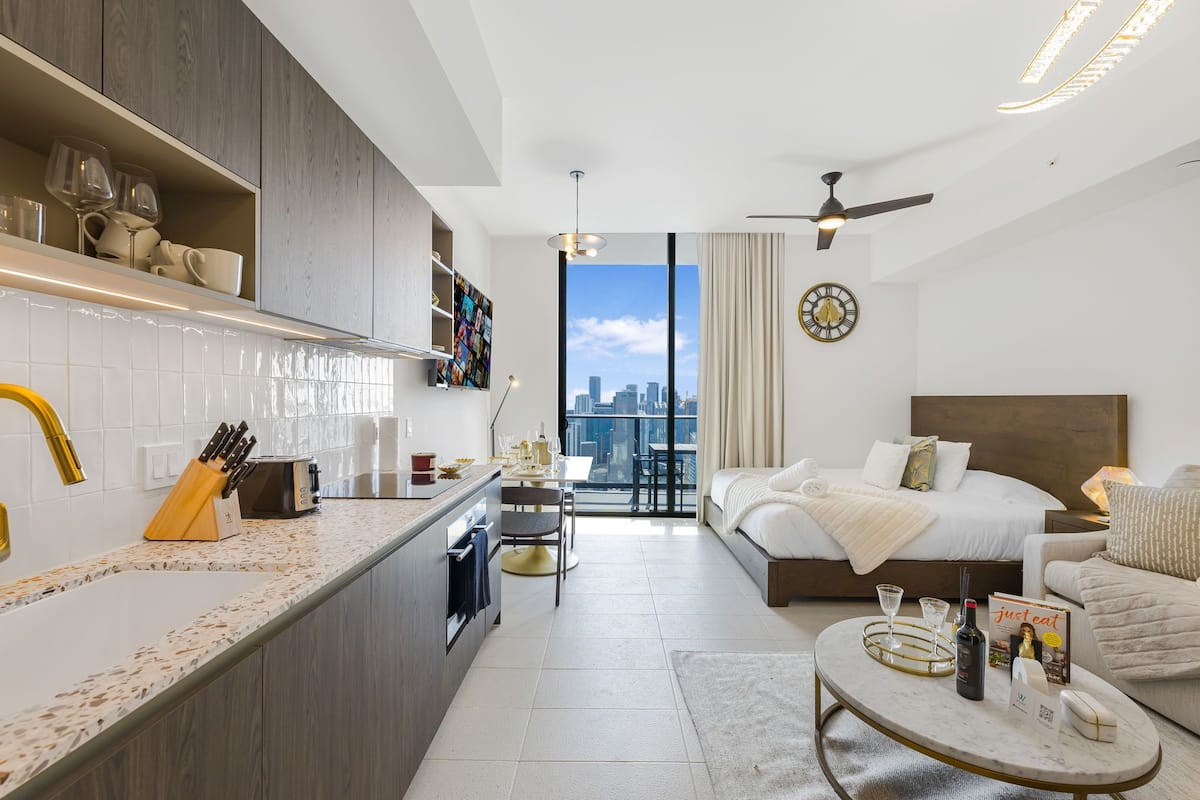 A modern hotel room with a kitchen, a dining area, and a bedroom.