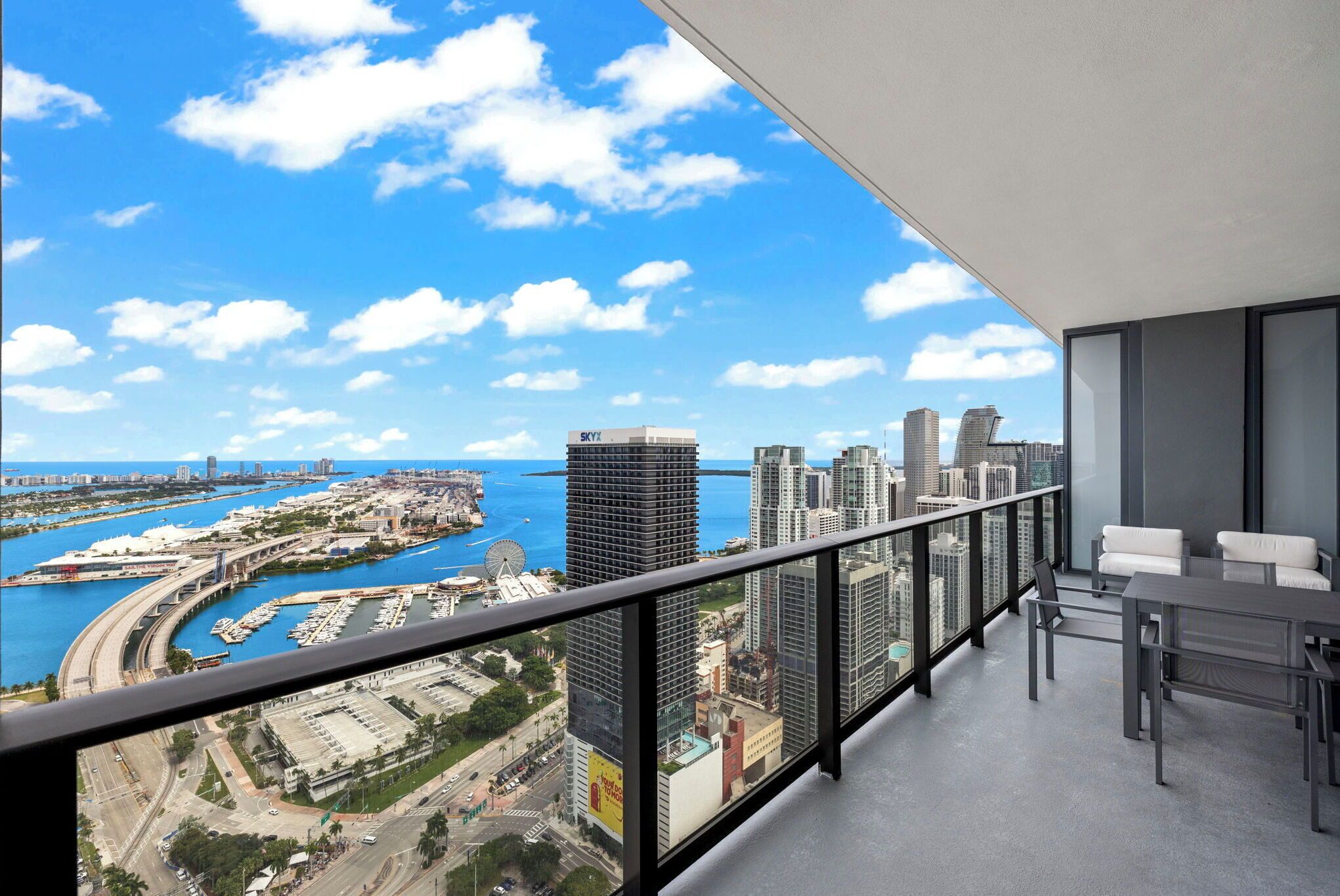 A balcony with a city view, including a marina and high-rise buildings.