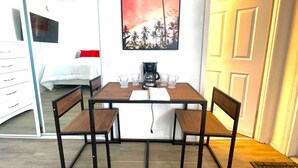 A dining area with a table, chairs, and a coffee maker. - Cozy new Daytona Beach studio with pool access,sunset and ocean views. (Daytona Beach)
