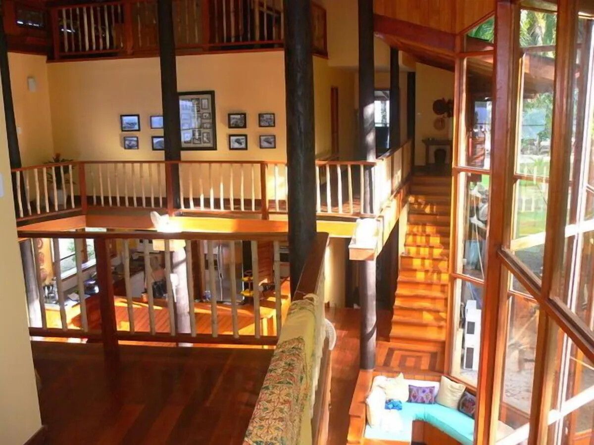 A multi-level wooden interior with a staircase, a balcony, and a view of the outdoors.