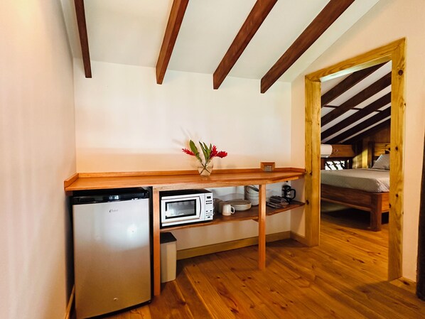 A compact kitchen with a built-in dishwasher, microwave, and wooden countertop. A small table with a vase of flowers is placed in the center. - Entire Resort of Bocas Beachfront Lodge "BBL" (Isla Carenero)