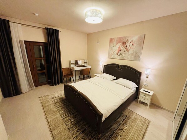 A bedroom with a bed, desk, chairs, and a painting on the wall. - Mellis Boutique (Cluj-Napoca)