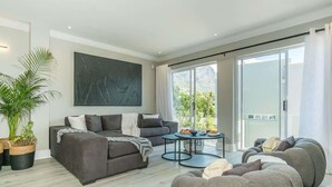 A modern living room with a grey sofa, a round coffee table, and a large abstract painting on the wall.