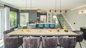 A modern kitchen with a central island, pendant lighting, and a staircase leading to a loft area.
