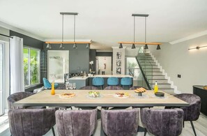 A modern kitchen with a central island, pendant lighting, and a staircase leading to a loft area.