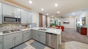 A modern kitchen with grey cabinets, a stainless steel microwave, and a dishwasher.