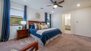A bedroom with a bed, nightstand, lamp, and a ceiling fan.