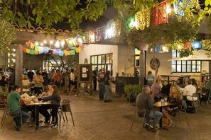 Un espace extérieur aménagé pour les repas, avec des tables et des chaises, entouré d’une cour pavée de briques.