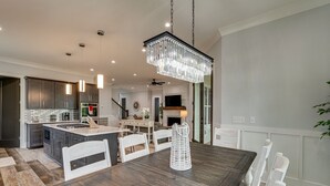 Een moderne keuken met donker houten kastjes, een centraal eiland, hanglampen en een kroonluchter.