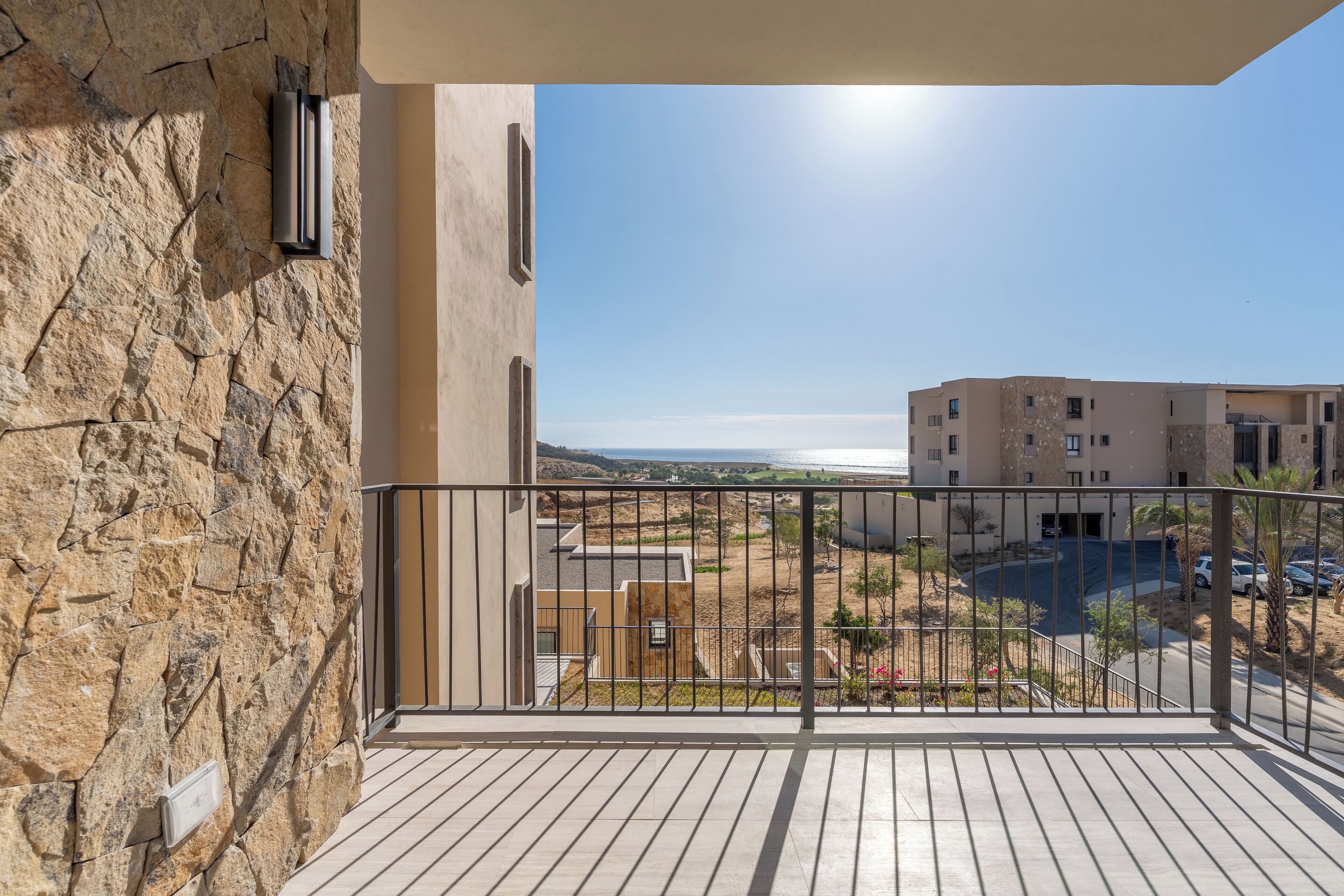 Ein Balkon mit Steinmauer, Blick auf eine Wohngegend und einem klaren Himmel.