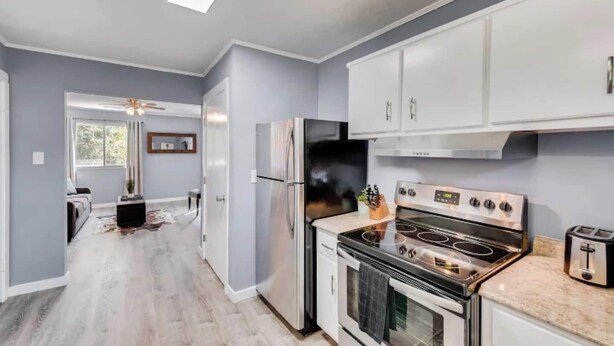 A modern kitchen with a built-in oven, a refrigerator, and white cabinetry.