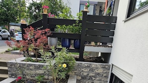 A garden with stone planters, a metal bollard, and a paved area leading to a building entrance.