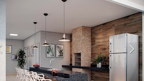 Una cocina moderna con una isla central, refrigerador de acero inoxidable, lámparas colgantes y una pared decorativa de ladrillo.