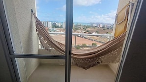 Un balcón con vistas a un paisaje urbano, una hamaca y un ventanal de vidrio.