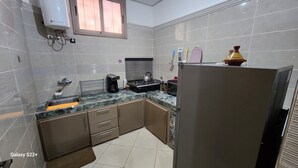 A compact kitchen with a gas stove, coffee maker, and a refrigerator.