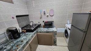A compact kitchen with a gas stove, microwave, toaster, and a washing machine.
