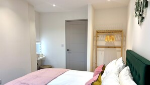 Une chambre à coucher bien rangée, avec un lit, une table de chevet et une porte.