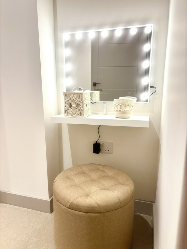 Un espace coiffeuse avec un miroir, des lampes et des boîtes de rangement.