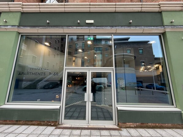 A building with large windows, a green facade, and a sign indicating 'Vespasian Apartments 1-64'.