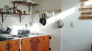Una cocina con armarios de madera, una encimera con estufa y ollas colgando.