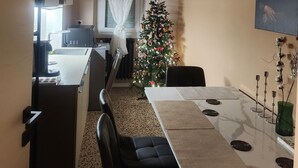 A modern kitchen with a dining area, a Christmas tree, and a painting of the Mona Lisa on the wall.