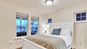 A bedroom with a white bed, two windows with blinds, a bedside lamp, and a view of the outside. - Dover Dreamin’ – Lake Life starts here! 3BD, 3BA Retreat, Steps from the Water (Dover)
