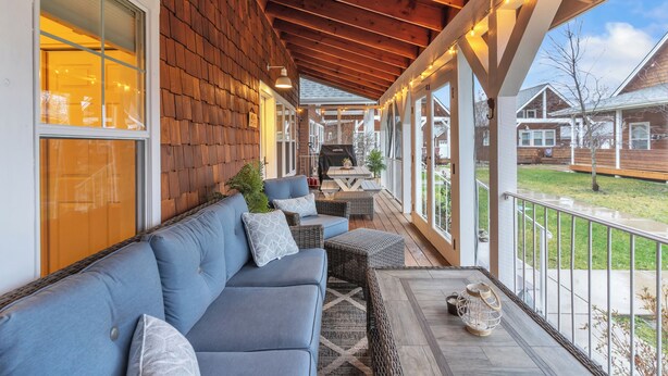 A covered porch with a blue sofa, wicker chairs, and a table. - Dover Dreamin’ – Lake Life starts here! 3BD, 3BA Retreat, Steps from the Water (Dover)