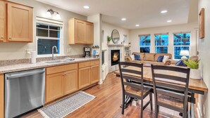 A modern kitchen with wooden cabinets, a dishwasher, and a dining area with a wooden table and chairs. - Dover Dreamin’ – Lake Life starts here! 3BD, 3BA Retreat, Steps from the Water (Dover)
