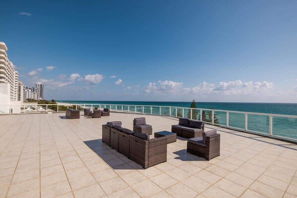Eine Dachterrasse mit Sitzgelegenheiten im Freien und Blick auf den Ozean.