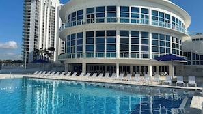 Ein Hotel mit Pool, Liegestühlen und einem modernen Gebäude mit Balkonen.