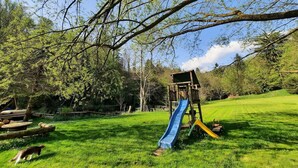 Ein Spielplatz mit Rutsche und Klettergerüst in einer grünen Parkanlage.